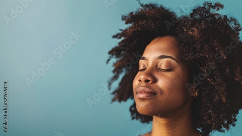 African American woman with afro hair and closed eyes, relaxed expression against blue background