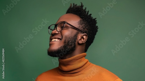 Photo of a happy handsome young black man wearing glasses and a turtleneck sweater against a green background in a studio