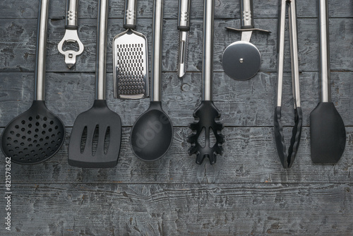 Variety of Kitchen Utensils on Rustic Wooden Background - Spatula, Knife, Tongs, and More photo