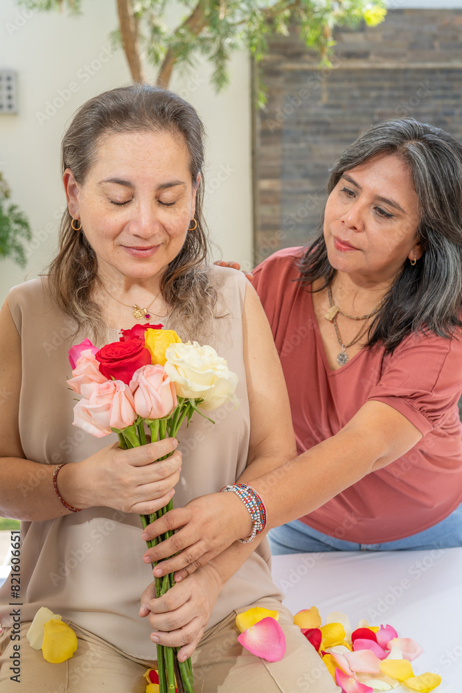 Woman giving a bouquet of roses to another woman Woman giving a bouquet of roses to another woman