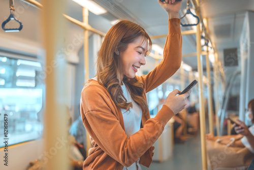 Happy young Asian woman passenger smile and using smart mobile phone in subway train station, lifestyle, transportation. © oatawa