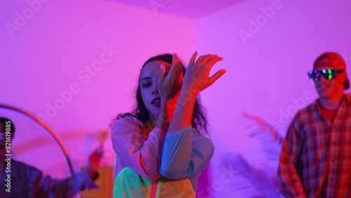 Hispanic hipster wear colorful cloth and waving to freestyle music. Professional break dancer moving to lively beat with neon light and led light with modern studio surrounded by friend. Regalement. photo