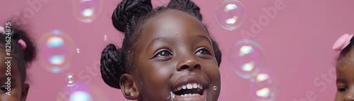 Seven-year-old African girl happily plays with bubbles against a magenta backdrop, featuring ample space on the left © Fokasu Art