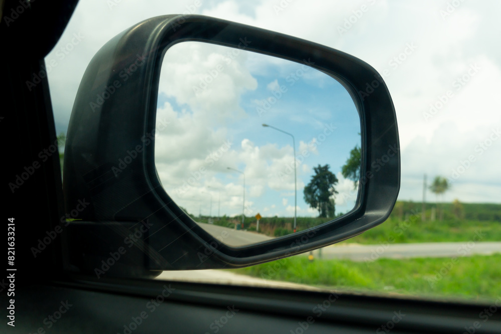 Abstract mirror wing of car. Looking back for trip to travel with green meadow meandow under blue sky. on roads without cars.