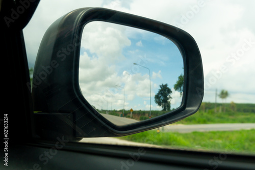 Abstract mirror wing of car. Looking back for trip to travel with green meadow meandow under blue sky. on roads without cars.