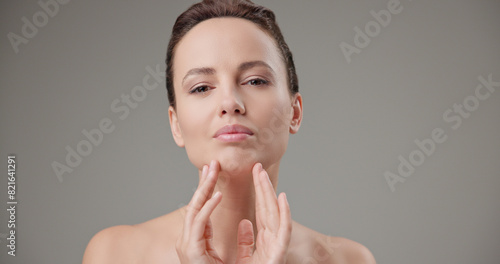 Beauty, health, cosmetics, anti-aging therapy and skin care concept - young beautiful brunette Caucasian woman touching her face skin with her hands, posing and looking at the camera as in a mirror