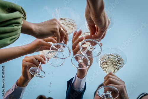 Foto Group of people clinking glasses with martini against the sky during party summer outdoor, closeup