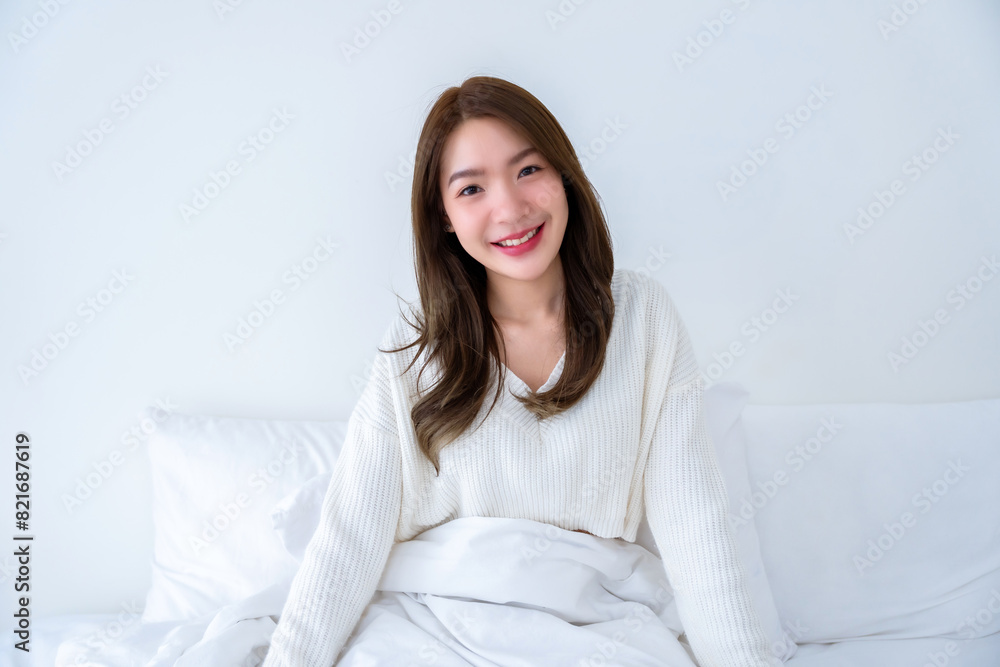 Portrait front of young asian woman smiling sitting on bed in bedroom and looking at camera, Facial expression happy, beauty skin, good healthy Portrait front of young asian woman smiling sitting on bed in bedroom and looking at camera, Facial expression happy, beauty skin, good healthy