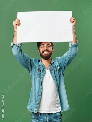 A young smiling man holds a white blank sign in his raised hands. 