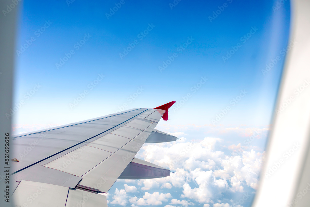 Obraz premium Clear blue sky with fluffy ornamental cumulus clouds, panoramic view from an airplane, wing close-up.