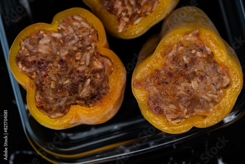 Frozen stuffed peppers filled with meat and rice, on dark black background, semi-finished, ready for cooking. Convenience and homemade frozen healthy meals.