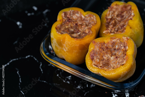 Frozen stuffed peppers filled with meat and rice, on dark black background, semi-finished, ready for cooking. Convenience and homemade frozen healthy meals.