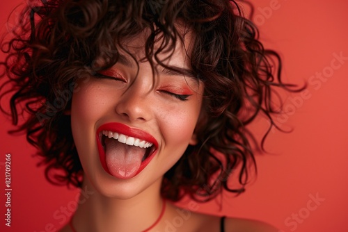 Stunning fashion portrait of a youthful and happy lady with impeccable skin and striking evening makeup  flaunting her wild side with a playful tongue gesture.