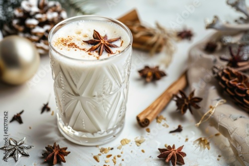 A festive holiday drink made with almond milk, topped with star anise and cinnamon, surrounded by holiday decorations including pinecones and cinnamon sticks.