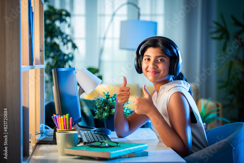Indian asian teenage girl student using headphone and computer for studying at home © StockImageFactory
