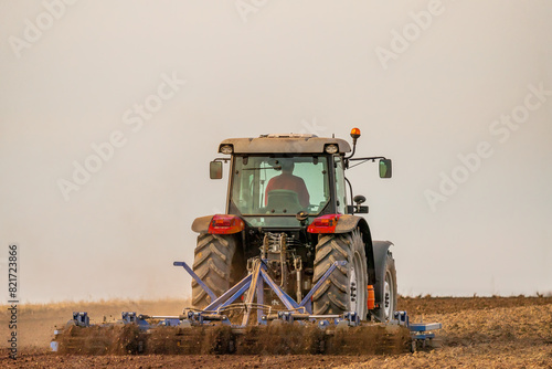 A tractor with plow in action, turning over the soil on a sunny day
