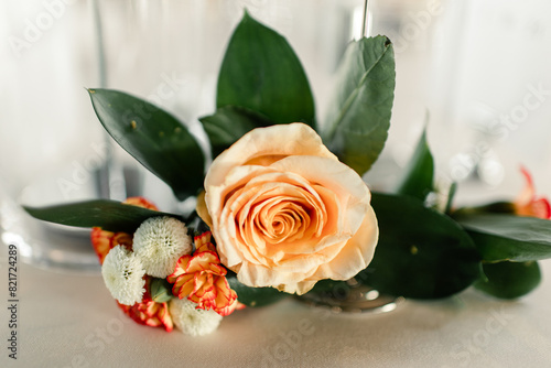 Close-up of an elegant peach rose centerpiece with green leaves photo
