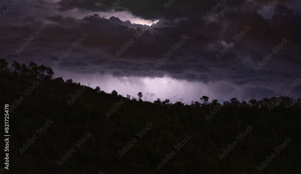 Dark clouds over a silhouette of trees at night, storm looming Dark clouds over a silhouette of trees at night, storm looming