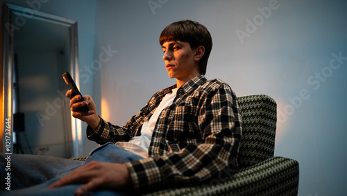 Cool guy sitting in a armchair and browsing on hisr mobile phone at the studio