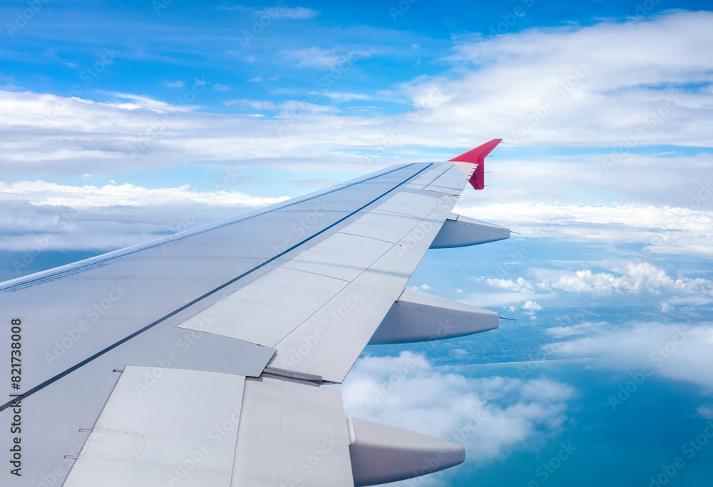 Fototapeta premium Clear blue sky with fluffy ornamental cumulus clouds, panoramic view from an airplane, wing close-up.