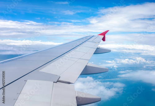 Clear blue sky with fluffy ornamental cumulus clouds, panoramic view from an airplane, wing close-up. © paul