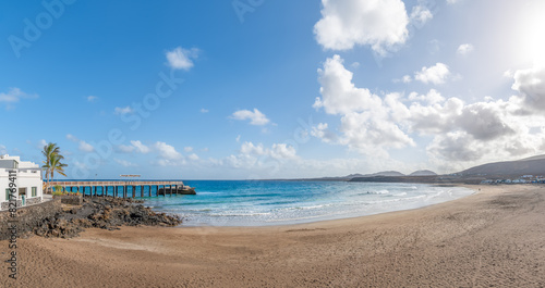 Landscape with Arrieta Beach in Lanzarote, Canary Islands, featuring a sandy shore, crystal-clear waters, and stunning coastal views