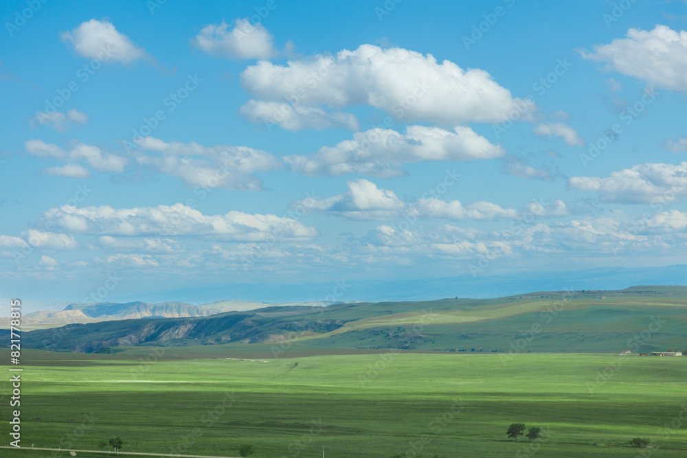 Green field in countryside at sunny day. Beautiful landscape in the mountains. Grassy field and hills. Travel Georgia Green field in countryside at sunny day. Beautiful landscape in the mountains. Grassy field and hills. Travel Georgia