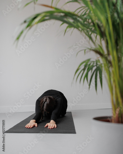 person in black clothes practices yoga in pose of child. Taking care of the body and mental health. woman strives for Harmony, balance and healthy lifestyle. Yoga Center