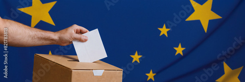Voting for the European Union election, a hand putting a ballot paper into a ballot box on a blue background with copy space © Illustration