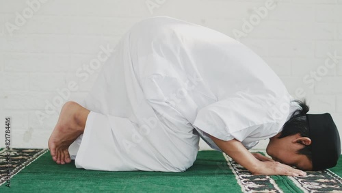Side View Of Young Asian Muslim Man Praying To Allah And Taking Sujud Or Prostration Position At Mosque photo
