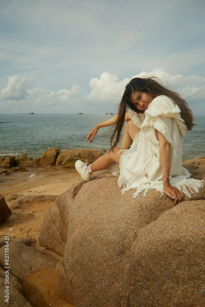 Woman sitting on the rocks at the beach in Vietnam Woman sitting on the rocks at the beach in Vietnam