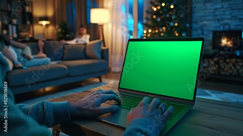 Wallpaper Mural This is a shot of a man's hands typing on a laptop with a green mockup screen. The living room has a woman relaxing on the sofa in the background. Torontodigital.ca
