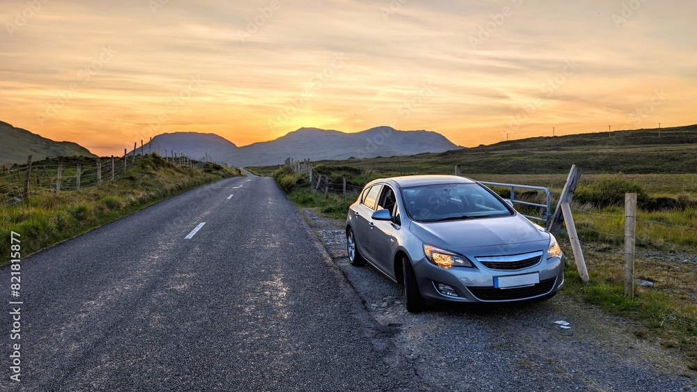 Car driving on empty scenic road trough nature and mountains at sunset, Connemara national park, county Galway, Ireland
