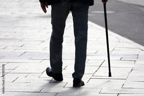 Silhouette of man walking with a cane down the street. Concept of old age, diseases of the spine or joint disease