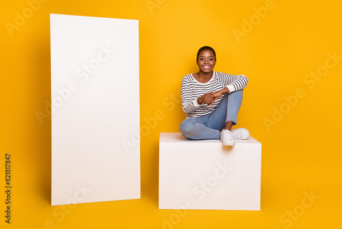 Full length photo of young pretty girl sit platform wear casual clothes isolated over yellow color background photo