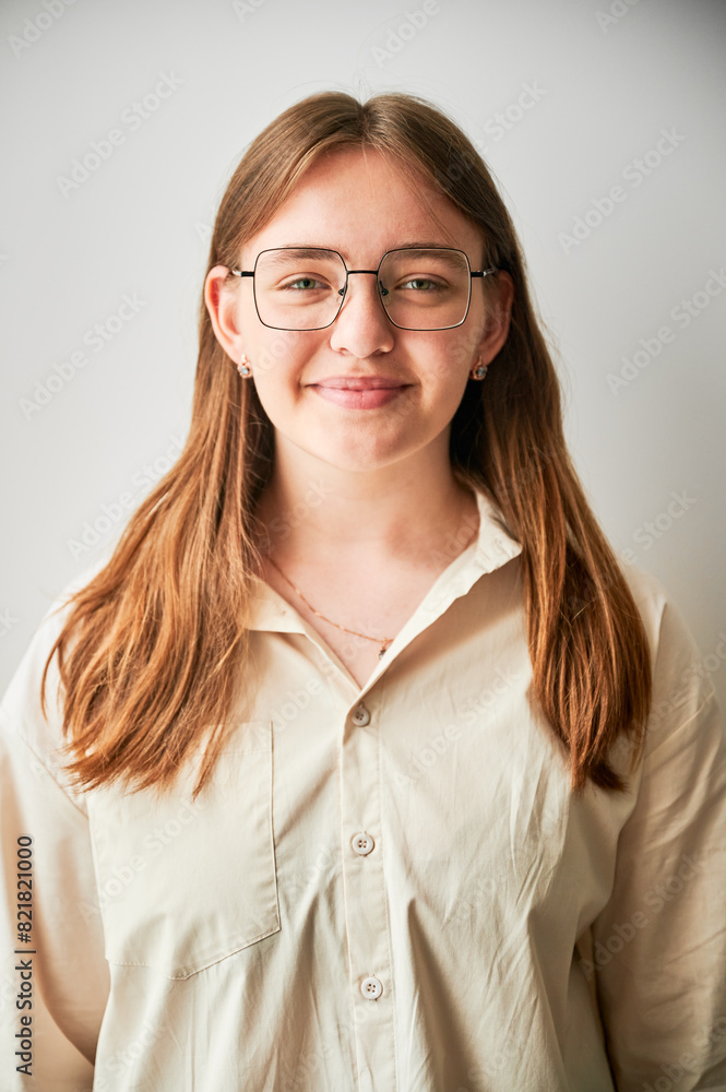 Portrait of beautiful girl smiling to camera. Cute girl in cream shirt and square glasses posing on white background.