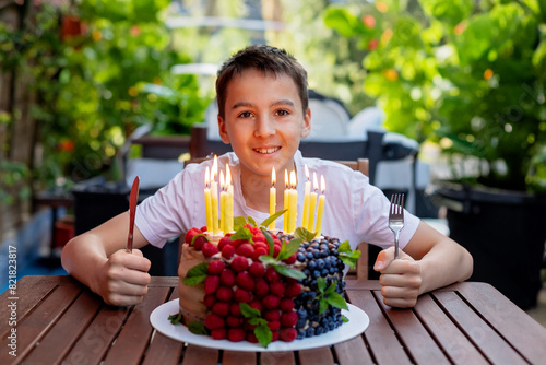 Cute school child, celebrating his birthday at home with siblings and homemade cake