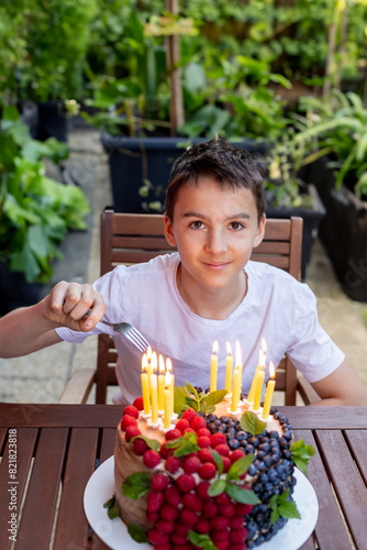 Cute school child, celebrating his birthday at home with siblings and homemade cake