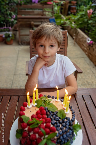 Cute school child  celebrating his birthday at home with siblings and homemade cake