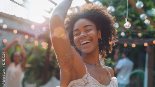 An attractive multicultural female dances and has fun on the front porch of a home. A young woman with a positive and joyful attitude relaxes at a summer garden party. photo