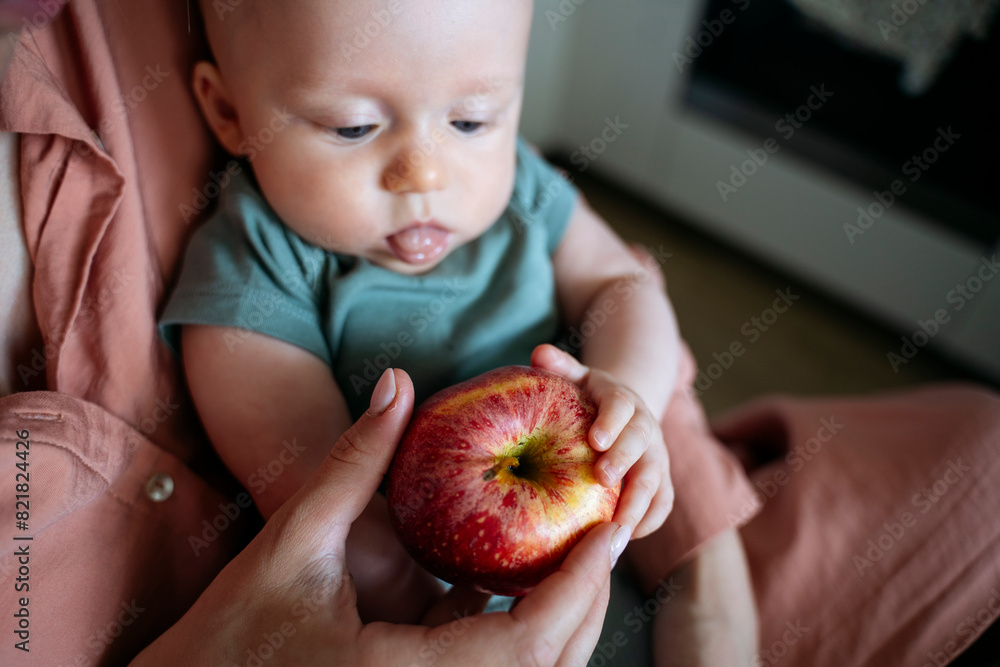 Cute baby boy and mother holding apple at home Cute baby boy and mother holding apple at home