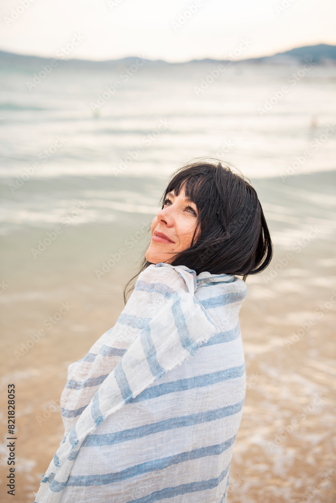 Thoughtful woman wrapped in scarf at beach Thoughtful woman wrapped in scarf at beach