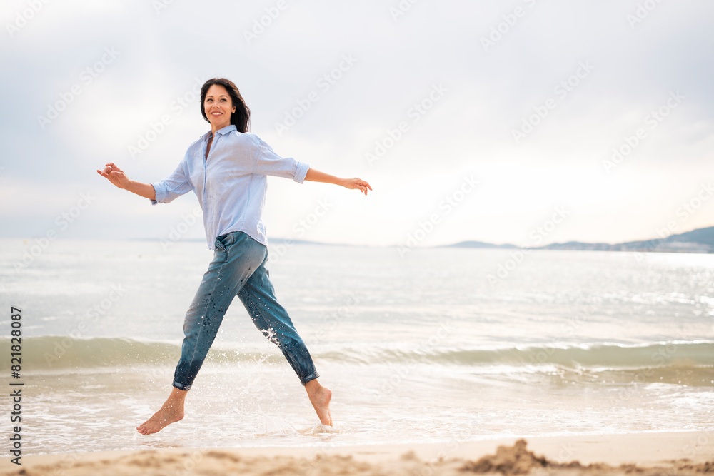 Mature woman running in water at beach Mature woman running in water at beach