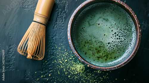 Cup of fresh matcha tea with bamboo whisk on black table