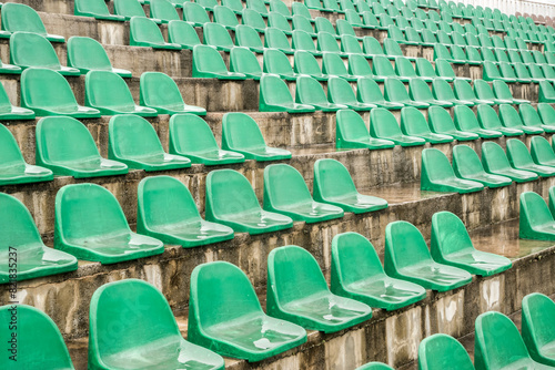 Green plastic stadium worn out chair seats in rows