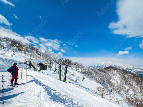 Single chair lifts in a ski resort and snowy peaks in a distant on a sunny day (Madarao Kogen, Nagano, Japan)