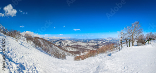 Panorama view of a steep slope and snow peaks a sunny day (Madarao Kogen, Nagano, Japan) photo