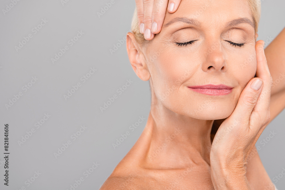 Close up cropped photo of smiling pretty retired woman show ideal skin peeling lotion cream empty space isolated on gray color background Close up cropped photo of smiling pretty retired woman show ideal skin peeling lotion cream empty space isolated on gray color background