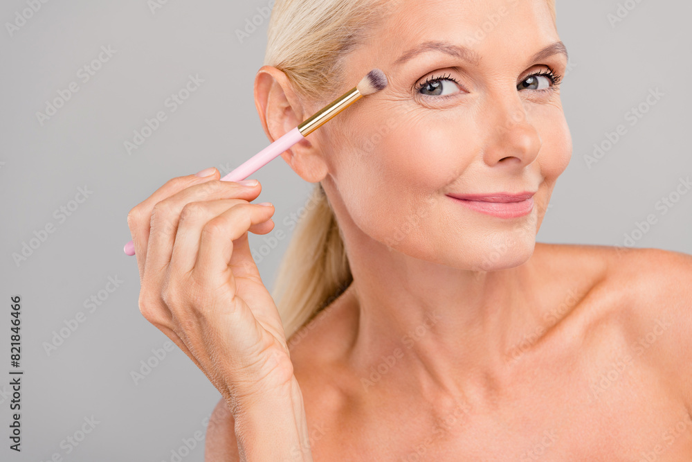 Photo of adorable shiny old woman naked shoulders applying visage empty space isolated grey color background Photo of adorable shiny old woman naked shoulders applying visage empty space isolated grey color background