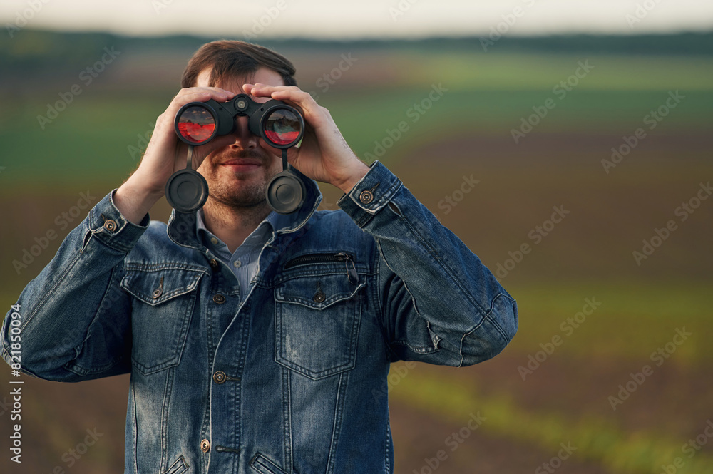 Portrait of man with binoculars that is standing outdoors on the agricultural field Portrait of man with binoculars that is standing outdoors on the agricultural field